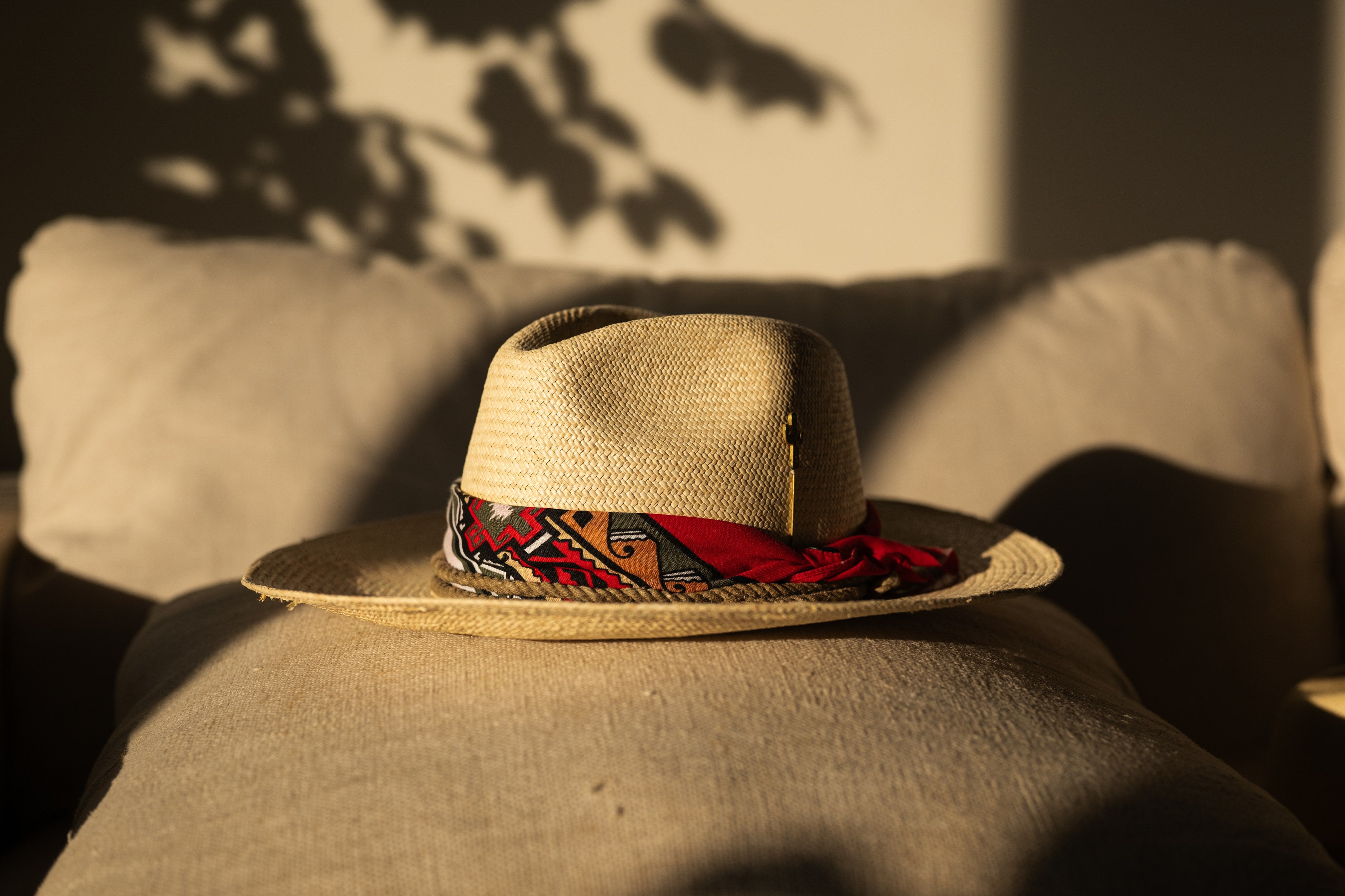 Firebird straw hat side profile, scarf band trailing across the wide flat brim.