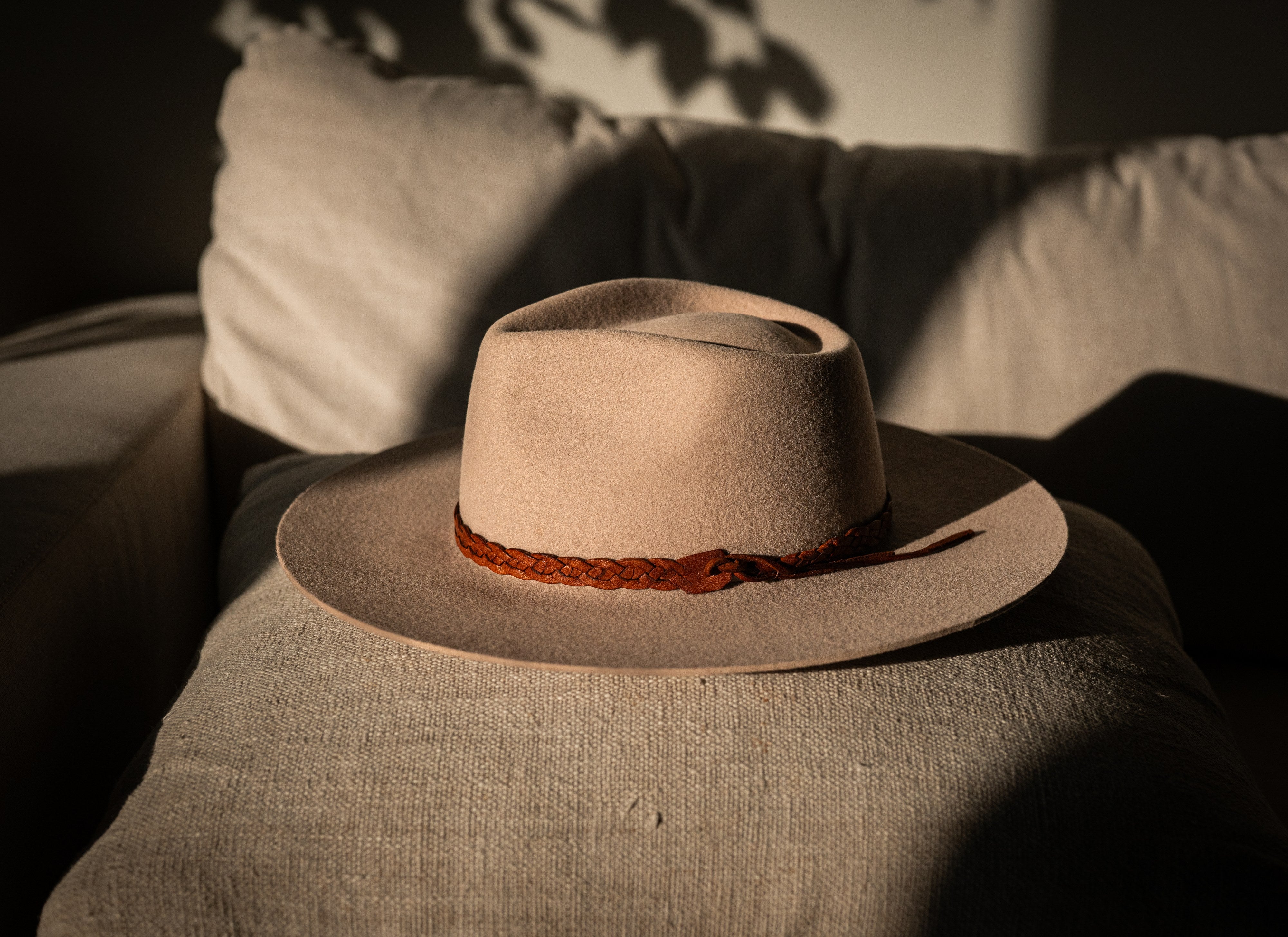 Le Souk bone wool-felt hat with braided cognac leather band, on linen in soft light.