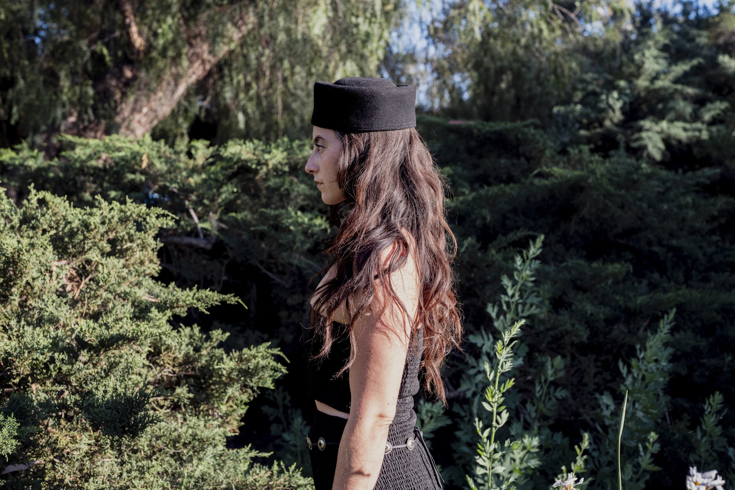 Pillbox black wool felt cap on model in indoor portrait setting, flat crown profile visible.