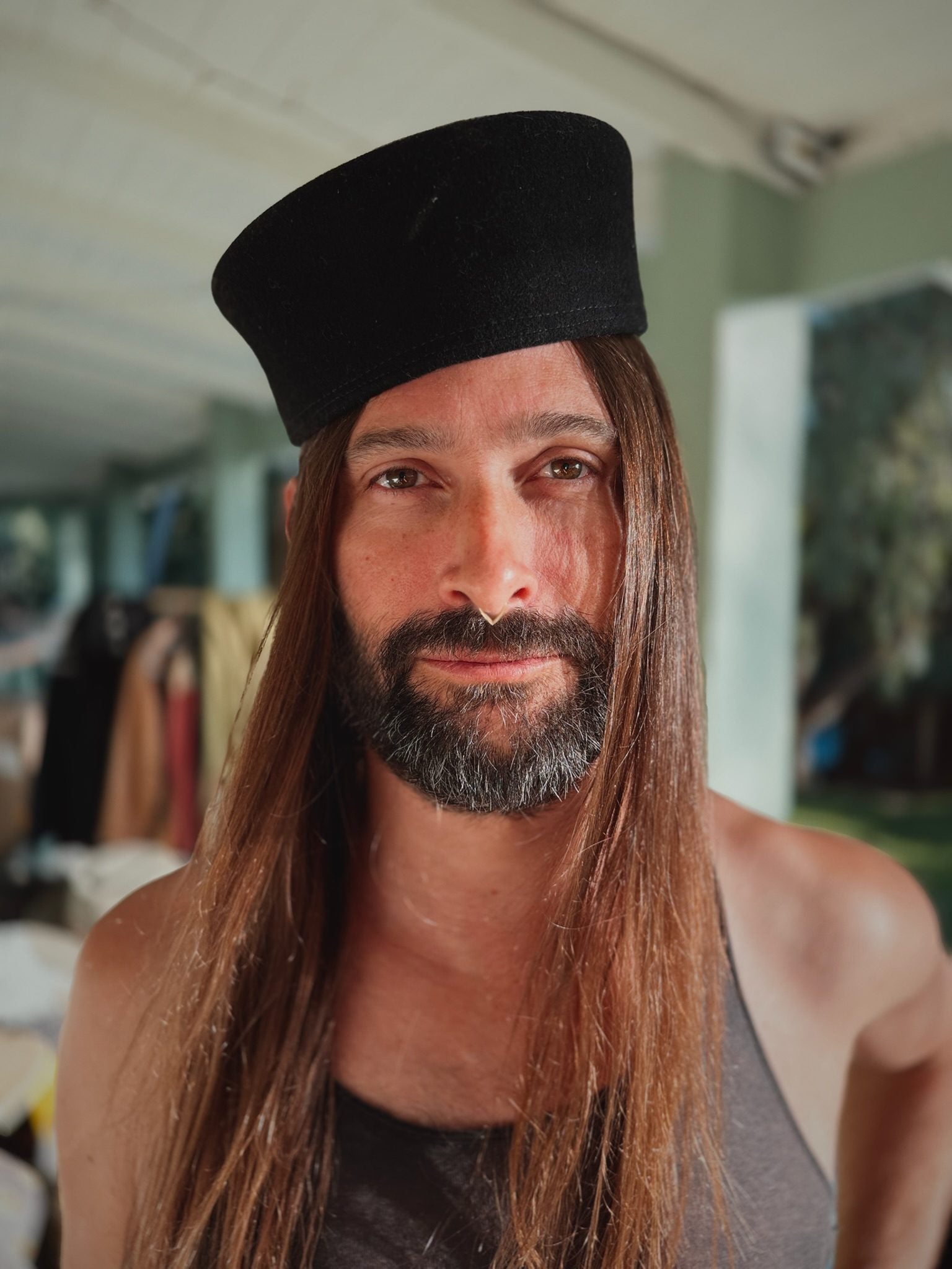 Pillbox black wool felt cap worn front view, structured flat crown sitting tall on the head.