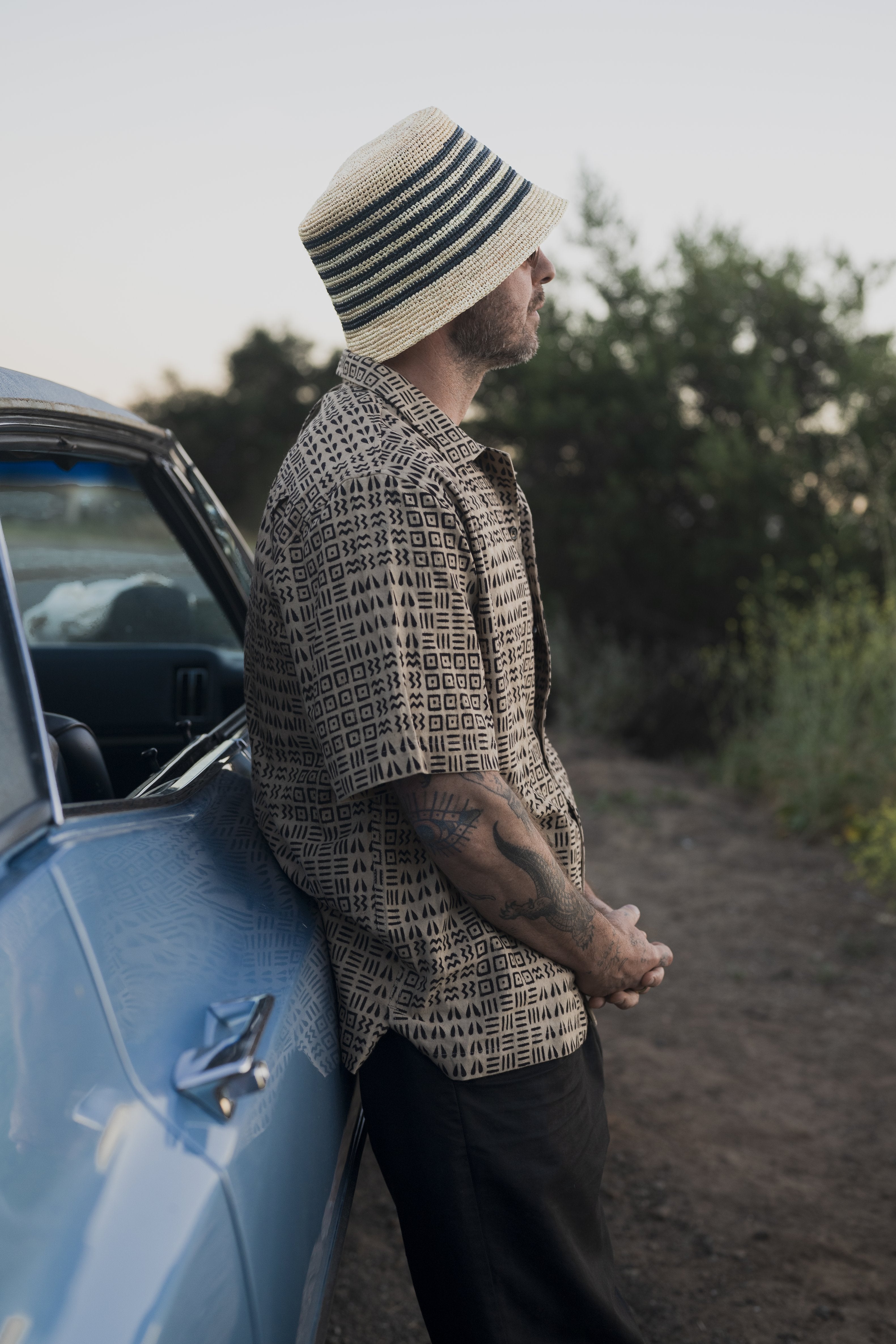 Racer Straw Bucket hat styled outdoors, lifestyle setting.
